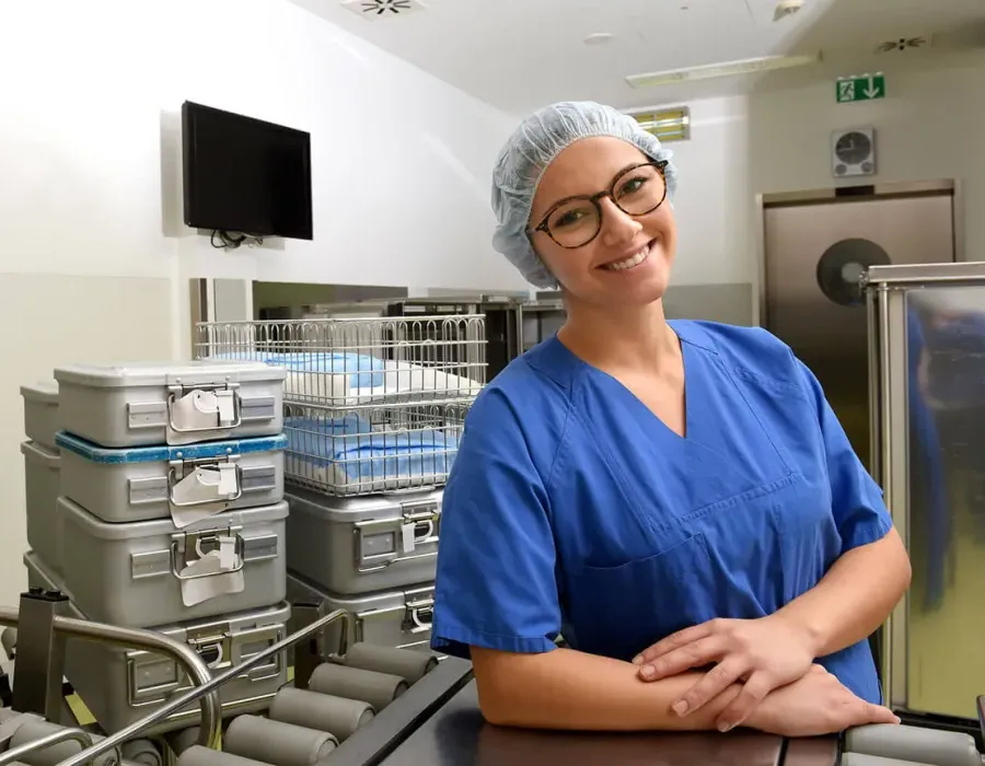 Sterile processing technician in lab wearing PPE posing and smiling for photo